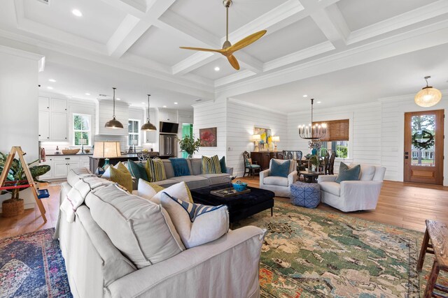 living room with wood finished floors, beamed ceiling, and ceiling fan with notable chandelier