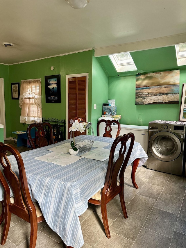 dining room featuring washer / dryer and vaulted ceiling with skylight