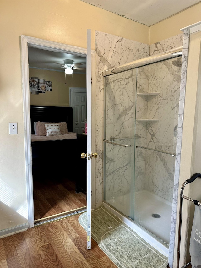 bathroom with a shower with door, hardwood / wood-style floors, and ceiling fan