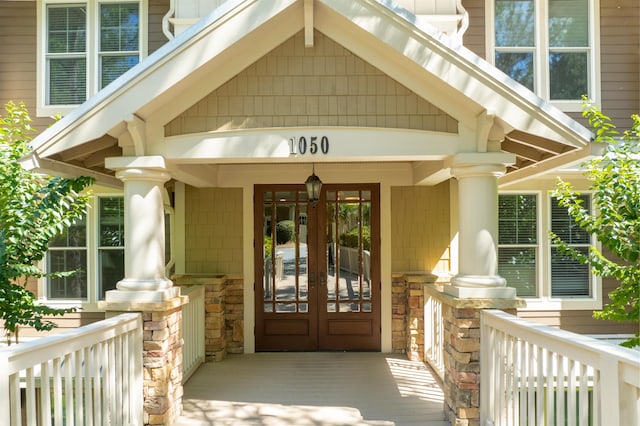 view of exterior entry featuring covered porch and french doors