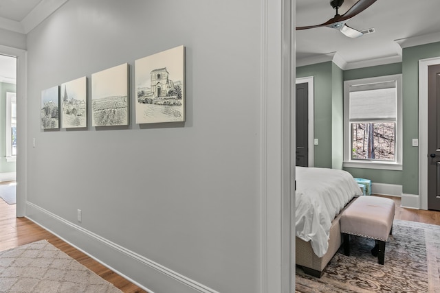 corridor featuring baseboards, wood finished floors, and ornamental molding