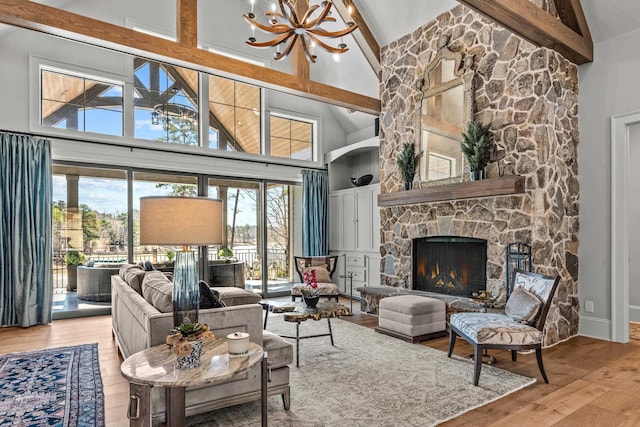 living area featuring beamed ceiling, a notable chandelier, high vaulted ceiling, hardwood / wood-style floors, and a stone fireplace