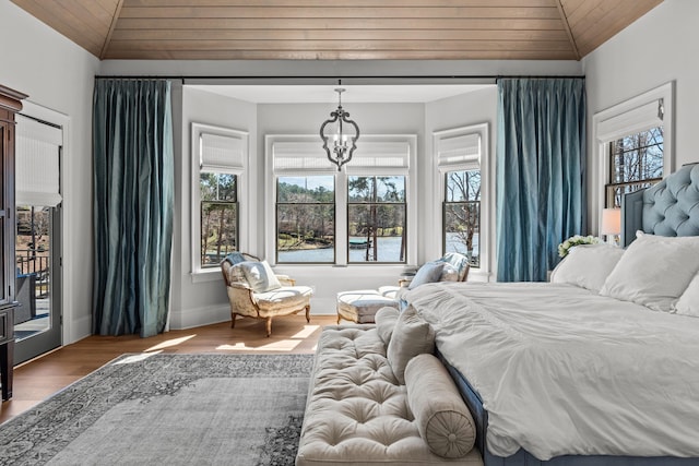 bedroom with lofted ceiling, wood finished floors, an inviting chandelier, wooden ceiling, and baseboards