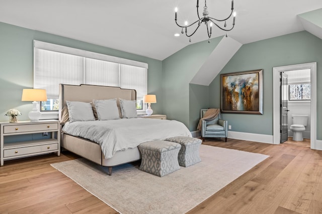 bedroom with baseboards, lofted ceiling, wood finished floors, and ensuite bathroom