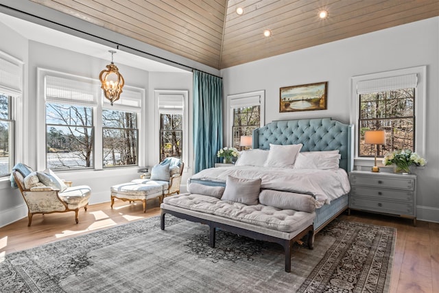 bedroom featuring an inviting chandelier, hardwood / wood-style flooring, and baseboards