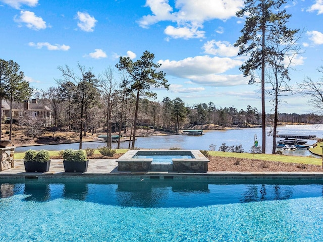 pool featuring an in ground hot tub and a water view