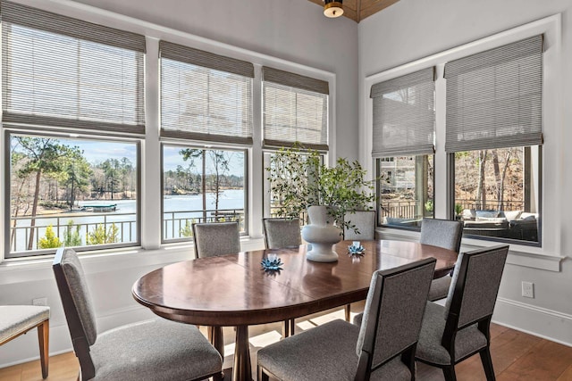 dining space featuring a water view, baseboards, and wood finished floors