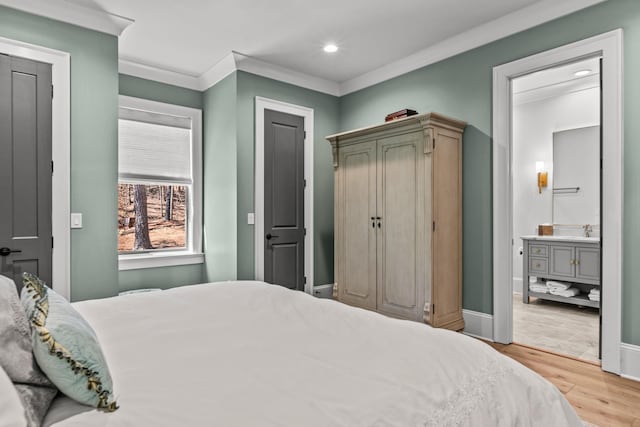 bedroom featuring crown molding, baseboards, recessed lighting, light wood-style flooring, and a sink