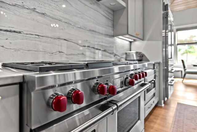 kitchen with range with two ovens, light wood-type flooring, tasteful backsplash, and gray cabinets