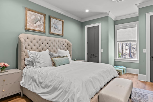 bedroom with light wood finished floors, a closet, baseboards, and ornamental molding