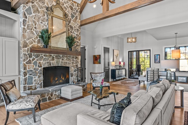 living area featuring a chandelier, beam ceiling, a fireplace, and wood finished floors