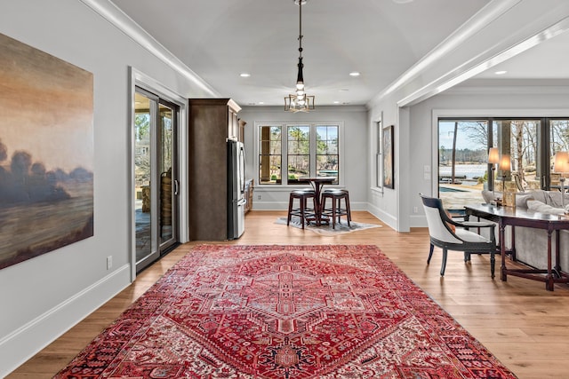 dining space featuring light wood finished floors, a chandelier, crown molding, and baseboards