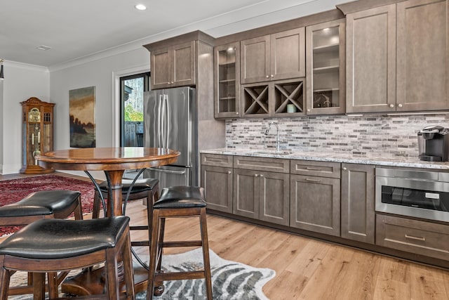 kitchen featuring light wood-style flooring, ornamental molding, a sink, freestanding refrigerator, and built in microwave