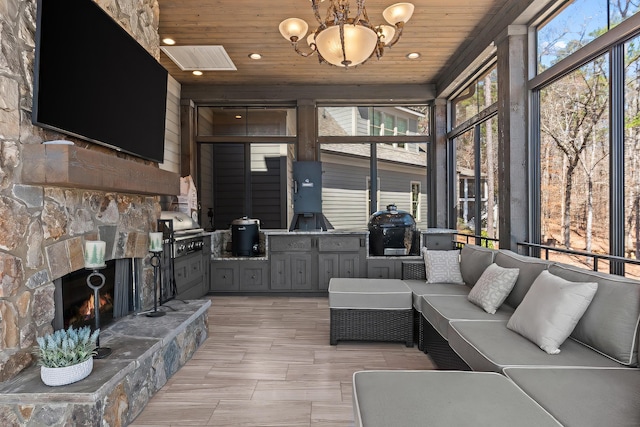 interior space featuring visible vents, an outdoor stone fireplace, wooden ceiling, and an inviting chandelier