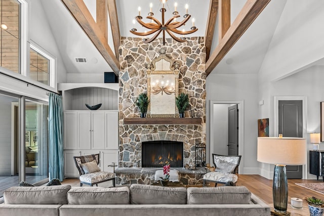 living room with visible vents, a chandelier, a stone fireplace, wood finished floors, and high vaulted ceiling