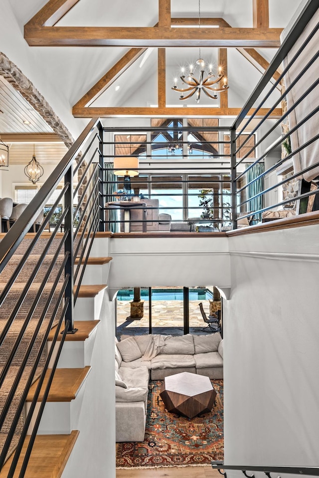 living room featuring beam ceiling, stairway, high vaulted ceiling, and an inviting chandelier