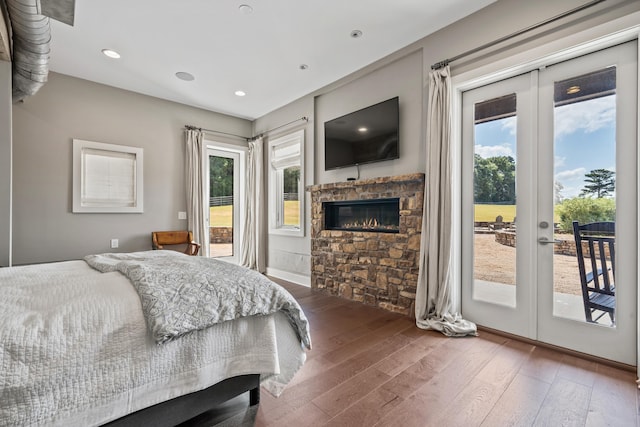 bedroom featuring multiple windows, access to outside, hardwood / wood-style floors, and a fireplace