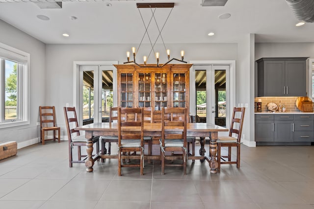 dining space with light tile patterned floors, an inviting chandelier, and french doors