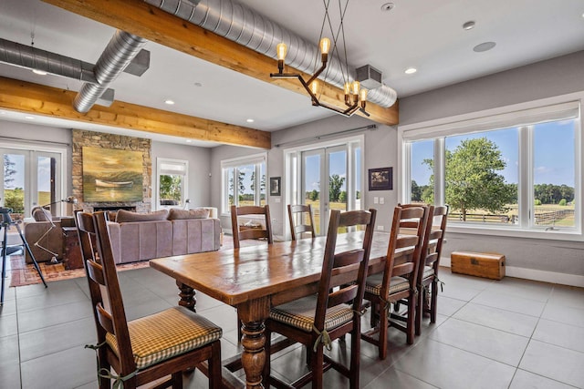 tiled dining space with a stone fireplace, a healthy amount of sunlight, and french doors