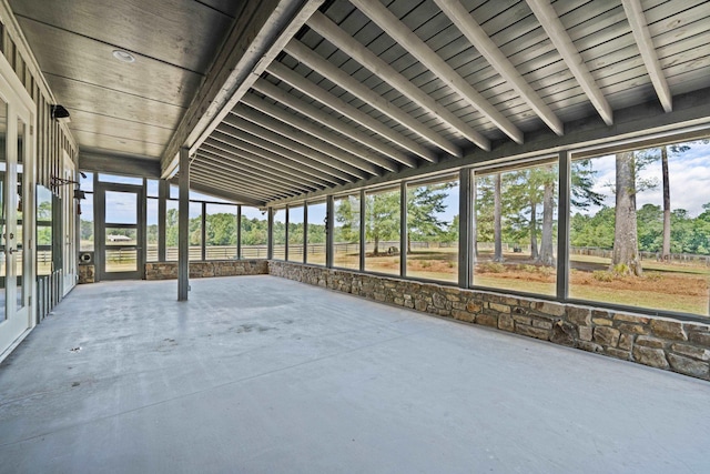 unfurnished sunroom with lofted ceiling with beams and a healthy amount of sunlight