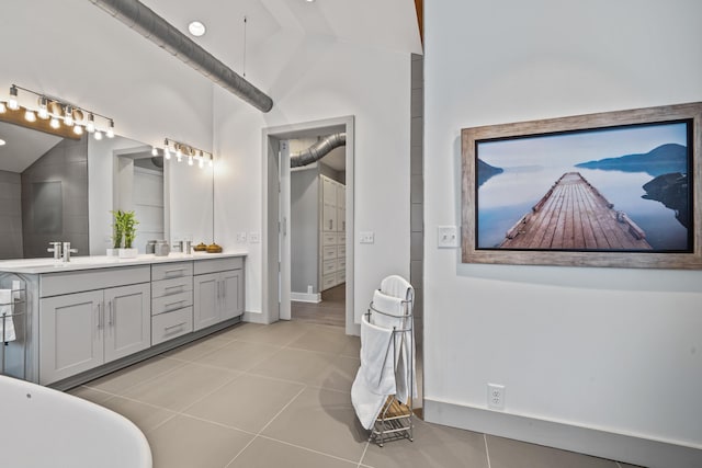 bathroom with vaulted ceiling, a tub, tile patterned floors, and vanity