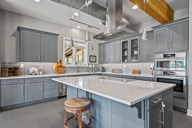 kitchen featuring appliances with stainless steel finishes, a kitchen breakfast bar, island range hood, a kitchen island, and decorative backsplash