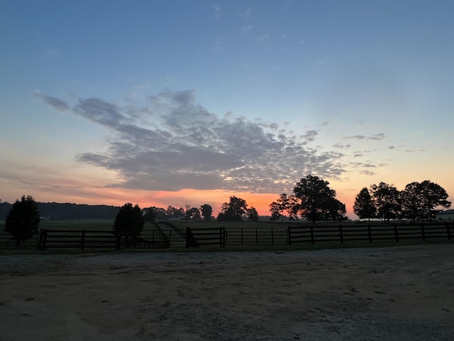 yard at dusk featuring a rural view