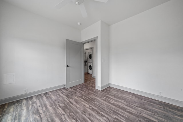 unfurnished room featuring wood-type flooring, stacked washer and clothes dryer, and ceiling fan