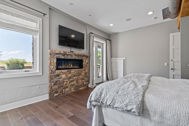 bedroom with dark wood-type flooring, a fireplace, and access to exterior