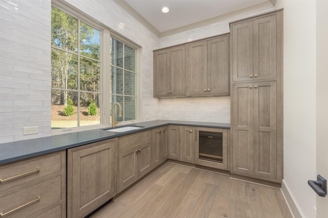 kitchen with tasteful backsplash, sink, and light wood-type flooring