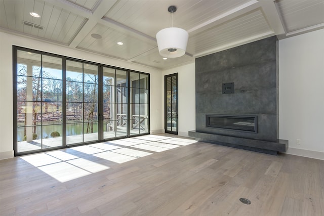 unfurnished living room with a water view, wood-type flooring, coffered ceiling, and a wealth of natural light