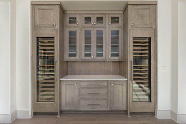 bar with wood-type flooring and beverage cooler