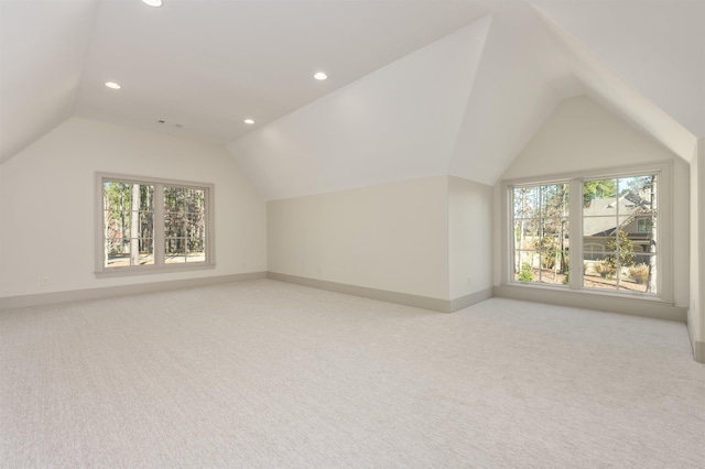 additional living space featuring vaulted ceiling, a healthy amount of sunlight, and light carpet