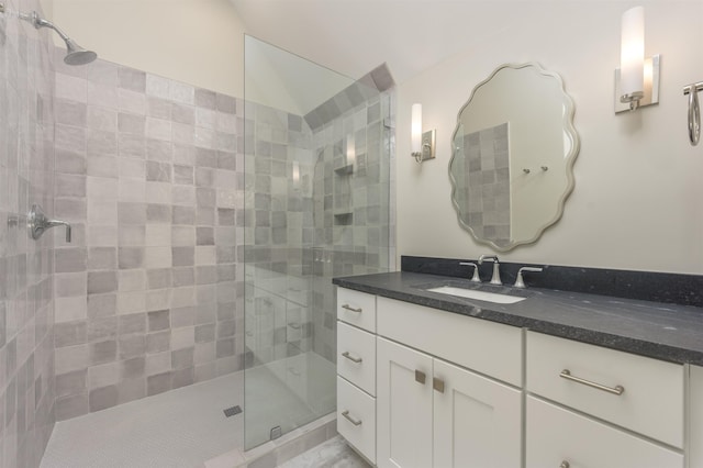 bathroom featuring vanity, lofted ceiling, and a tile shower