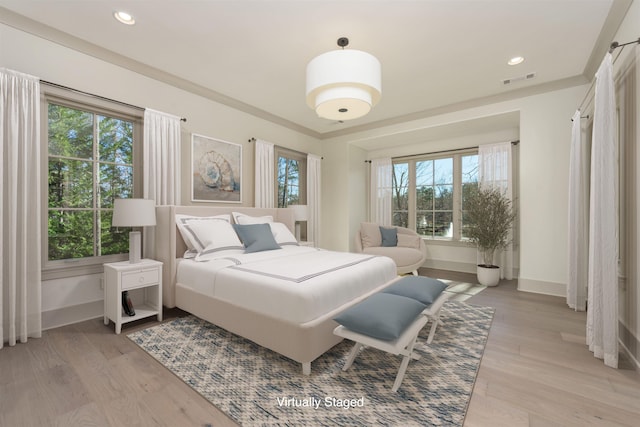 bedroom featuring multiple windows, crown molding, and light hardwood / wood-style floors