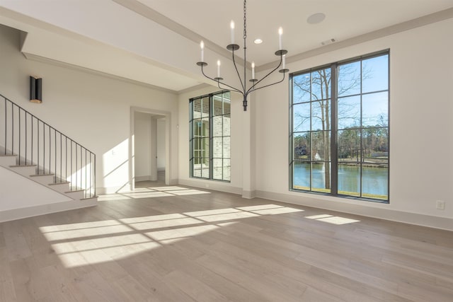 unfurnished dining area with a water view, a healthy amount of sunlight, a chandelier, and light hardwood / wood-style flooring