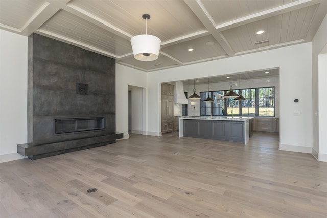 unfurnished living room with hardwood / wood-style flooring, a large fireplace, coffered ceiling, and beam ceiling