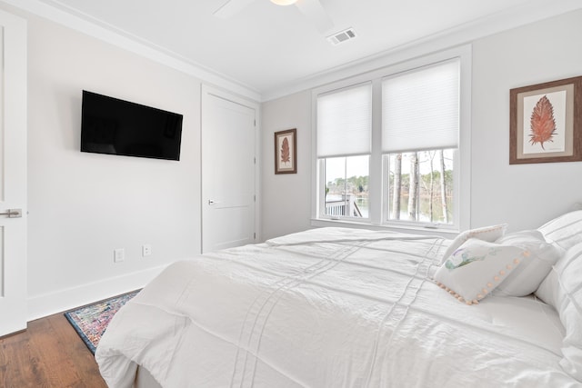 bedroom with ceiling fan, wood finished floors, visible vents, baseboards, and ornamental molding