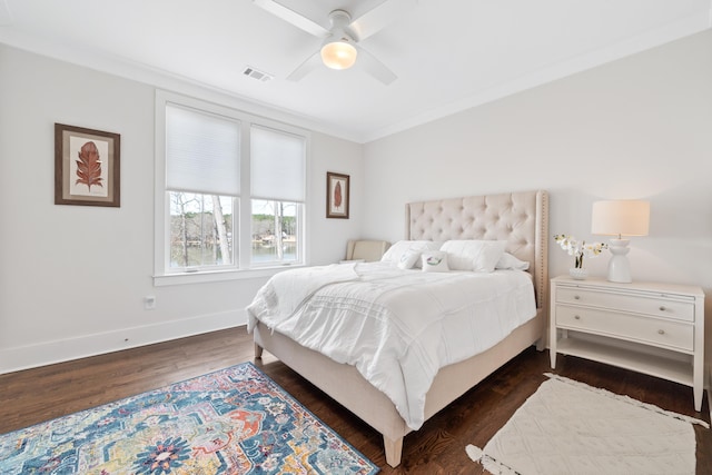 bedroom with dark wood-style flooring, visible vents, a ceiling fan, ornamental molding, and baseboards