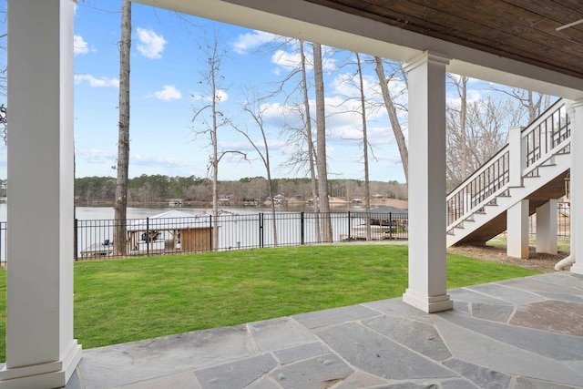 view of yard with a water view, fence, stairway, and a patio