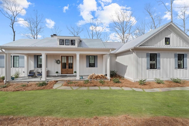 view of front of home featuring covered porch, metal roof, a front lawn, and board and batten siding