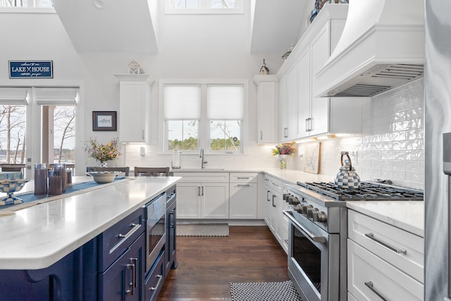 kitchen featuring blue cabinets, white cabinetry, premium range hood, and appliances with stainless steel finishes