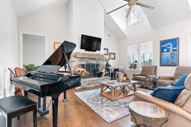 living room with ceiling fan, a stone fireplace, plenty of natural light, and wood finished floors