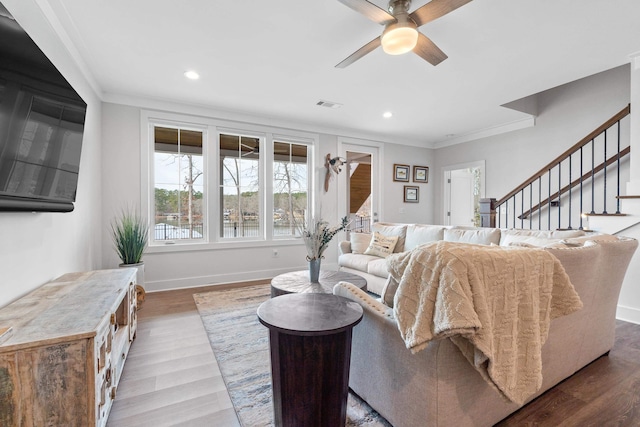 living room with wood finished floors, visible vents, baseboards, stairway, and crown molding