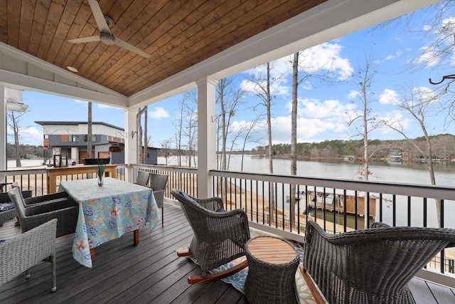 wooden terrace featuring a water view, a ceiling fan, and outdoor dining space