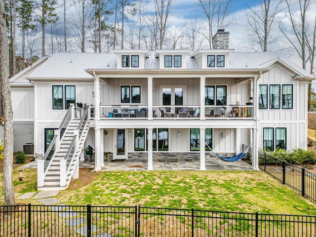 rear view of property featuring metal roof, fence private yard, central AC, a yard, and board and batten siding