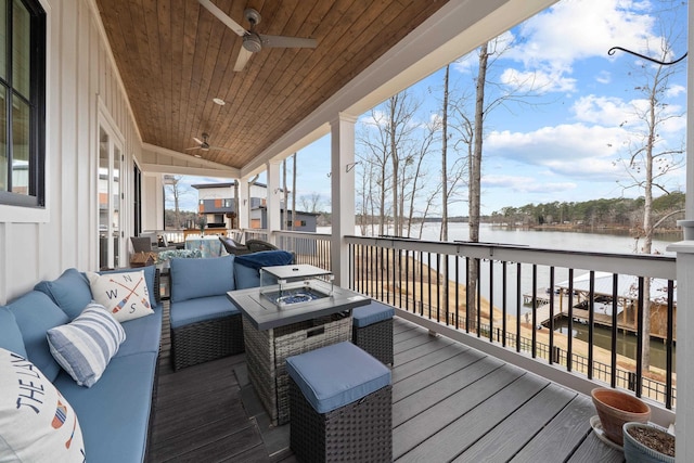 deck with a water view, a ceiling fan, and an outdoor living space with a fire pit