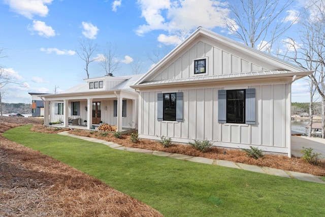 modern farmhouse style home featuring board and batten siding, a front yard, metal roof, and a porch