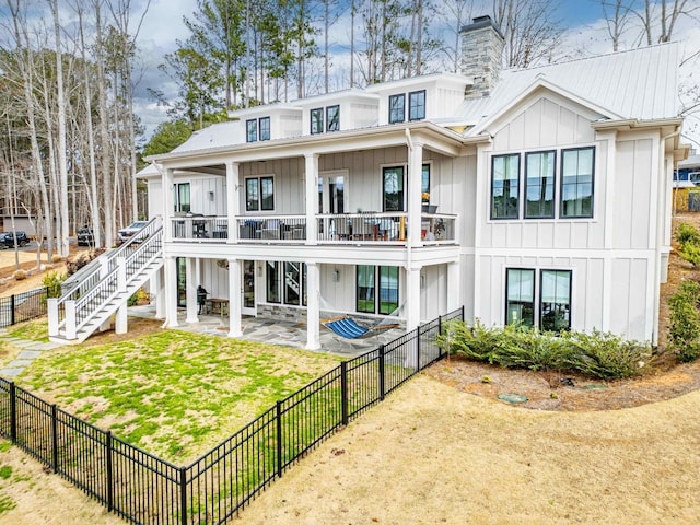 back of property with a fenced backyard, a chimney, a lawn, and board and batten siding