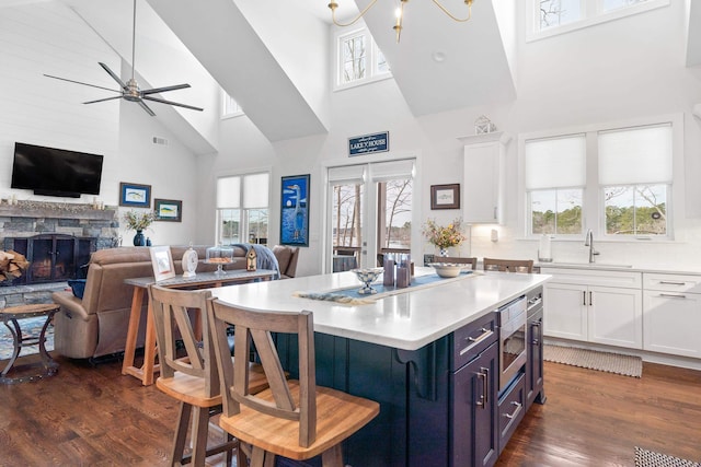 kitchen featuring white cabinets, stainless steel microwave, open floor plan, and light countertops